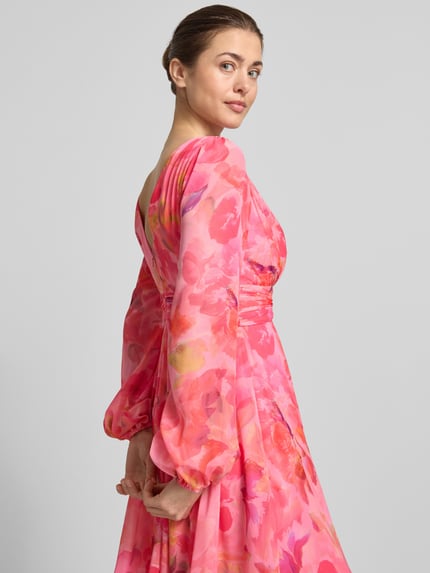 Vrouwenmodel draagt Cocktailkleid met Ballonärmeln und V-Ausschnitt van Jake*s Cocktail, roze met bloemen, chiffon, getailleerd model, mini-jurk, V-hals, rugdecolleté, rugritssluiting, ruglengte maat 36: 91 cm, borstwijdte maat 36: 40 cm, mouwlengte maat 36: 65 cm, detailopname rug.