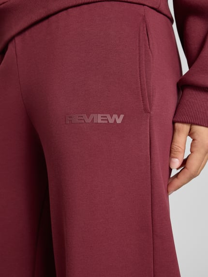 Frauenmodel trägt Straight Fit Sweatpants aus Baumwoll-Mix mit Label-Detail von REVIEW in Dunkelrot, Detailaufnahme, Damen Sweatpants von REVIEW, Baumwoll-Mix, Straight Fit, Label-Detail, elastischer Bund, Innenbeinlänge bei Größe S: 79 cm