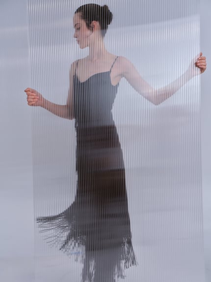 Frauenmodel trägt Midikleid mit Ausfransungen von Rabanne, schwarzer Acetat-Mix, tailliert, Spaghettiträger, Ganzkörperansicht von vorne.
