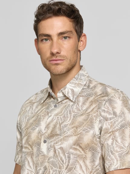 Männermodel trägt Regular Fit Freizeithemd mit Kentkragen von ARMANI EXCHANGE, beige-braunes Blattmuster, reine Baumwolle, Nahaufnahme Oberkörper.