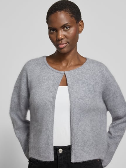 Frauenmodel trägt Strickjacke aus Wolle Kaschmir ohne Verschluss von BOSS in Hellgrau, unifarben, Struktur, Feinstrick, Nahaufnahme Oberkörper.