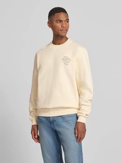 Männermodel trägt Sweatshirt mit rückseitigem Motiv-Print Modell 'Ben Faience' von Les Deux in Creme, Rundhalsausschnitt, Ganzkörperansicht von vorne