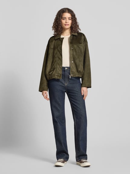 Frauenmodel trägt Regular Fit Blouson in Wildlederoptik Modell 'AMBER' von Only in Olivgrün mit Umlegekragen und Schulterriegel, Ganzkörperansicht von vorne.