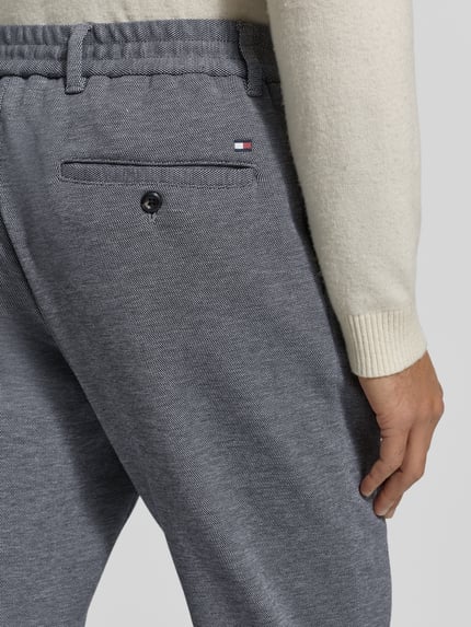 Männermodel trägt Relaxed Fit Schmale Hose aus reiner Baumwolle Modell 'HARLEM' von Tommy Hilfiger, Two-Tone-Optik, Detailaufnahme Rückansicht.