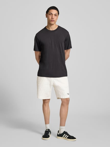 Männermodel trägt Herren Shorts mit Logo-Stitching Modell 'Jovren' von Pegador im Loose-Fit Material-Mix, Ganzkörperansicht von vorne.