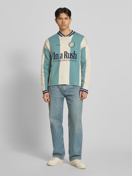 Männermodel trägt Strickpullover mit Label-Stitching Modell 'Overdrive' von PROHIBITED in Mint, Beige und Blau, reine Baumwolle, Relaxed Fit, Ganzkörperansicht von vorne.
