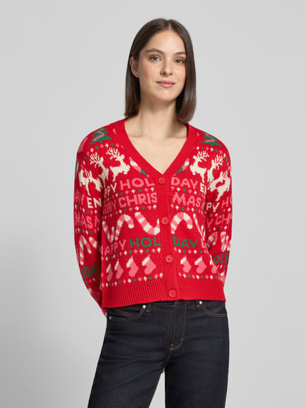 Frauenmodel trägt Cardigan mit weihnachtlichem Motiv-Strick von VERO MODA, mehrfarbiges Jacquard-Allovermuster, Knöpfe, Ganzkörperansicht von vorne.