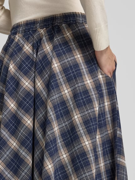 Frauenmodel trägt Midi-Rock mit asymmetrischem Saum Modell 'VMTILDA' von VERO MODA, kariertes Allover-Muster, Webware, Nahaufnahme Oberkörper.