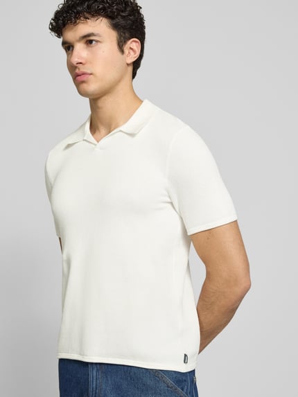 Männermodel trägt Slim Fit Poloshirt mit Strukturmuster van REVIEW in wit katoen met V-hals, slanke fit, voorkant, halftotaalopname.