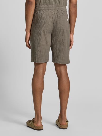 Männermodel trägt Shorts mit elastischem Bund und Strukturmuster von Lindbergh aus Baumwoll-Mix mit Stretch-Anteil, Loose-Fit, Ganzkörperansicht Rückansicht.