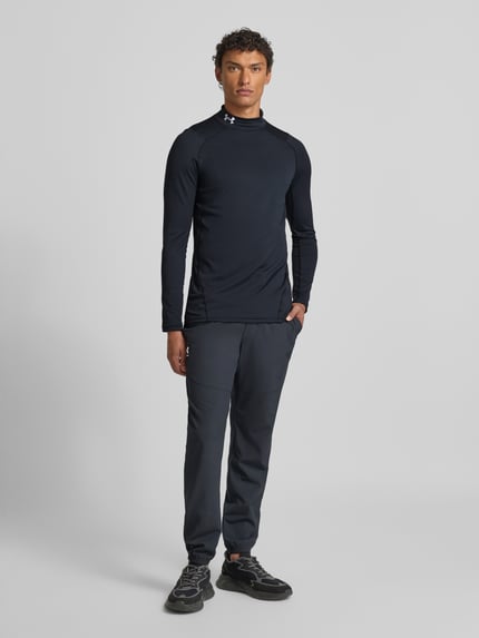 Męski model nosi Longsleeve mit Stehkragen von Under Armour, czarny, slim fit, materiał z domieszką stretchu, widok całej sylwetki z przodu.