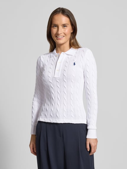 Frauenmodel trägt Sweter z dzianiny z ściegiem warkoczowym, kołnierzykiem polo, listwą guzikową, wyhaftowane logo, krój slim fit, bawełna, Polo Ralph Lauren, długość tyłu 63 cm, długość rękawów 66 cm, Ganzkörperansicht von vorne.