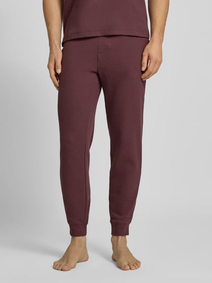 Männermodel trägt Relaxed Fit Pyjama-Hose aus Baumwoll-Mix Modell 'AUSTIN PANTS' von HUGO, unifarben, Waffel-Struktur, Label-Print, Regular-Fit, Tunnelzug, seitliche Eingrifftaschen, Ganzkörperansicht von vorne.