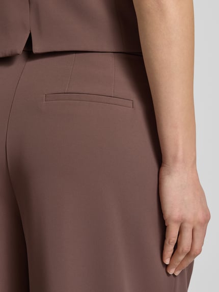 Vrouwenmodel draagt Wide Leg Stoffhose mit Raffungen van Christian Berg Cocktail in bruin, elastische materiaalmix, detailopname heup.