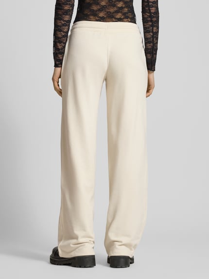 Frauenmodel trägt Wide Fit Sweatpants mit Viskose-Anteil von Review, cremefarben, elastischer Bund, Tunnelzug, Baumwoll-Mix, Ganzkörperansicht Rückansicht.