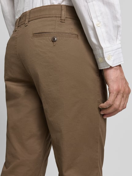 Męski model nosi Straight Fit Hose mit Gesäßtaschen von MCNEAL, brązowa bawełna, kieszenie z tyłu, zapięcie na guzik i zamek, Szerokość w rozmiarze 50: 46 cm, długość nogawki 83 cm, detal tylnej części spodni, zbliżenie na tył.