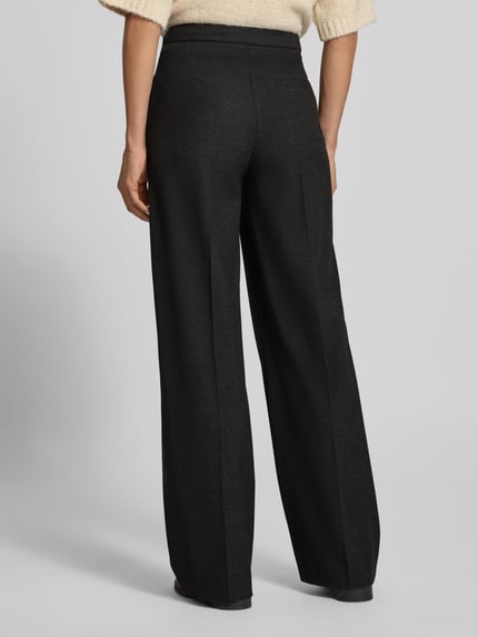 Frauenmodel trägt Regular Fit Jogpants mit Bundfalten von MARC O'POLO in Melange-Optik, Webware mit feinem Webmuster, Ganzkörperansicht Rückansicht.