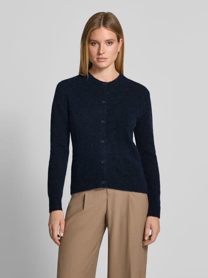 Frauenmodel trägt Regular Fit Cardigan aus Woll-Alpaka-Mix Modell 'NOR' von Samsøe Samsøe in Dunkelblau, Strick-Optik, Rundhalsausschnitt, durchgehende Knopfleiste, elastisches Material, Ganzkörperansicht von vorne.