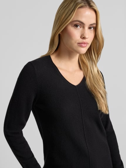 Frauenmodel trägt Strickpullover aus Kaschmir mit V-Ausschnitt von Christian Berg Woman, Schwarz, Slim Fit, Rollsaum, Nahaufnahme Oberkörper.