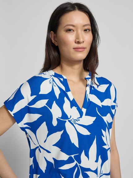 Vrouwenmodel draagt Relaxed Fit T-Shirt aus Viskose-Mix van s.Oliver RED LABEL met blauw-wit florale print, Henleyhals, korte mouw, jersey, allover patroon, Nahaufnahme bovenlichaam.