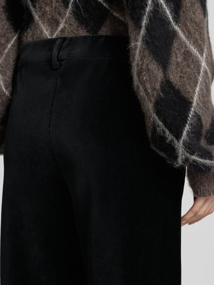Frauenmodel trägt Regular Fit Cordhose mit Bundfalten Modell 'MAINE' von BRAX, Cordstruktur, unifarben, schwarze Optik, Gesäßtaschen, Nahaufnahme Rückansicht.