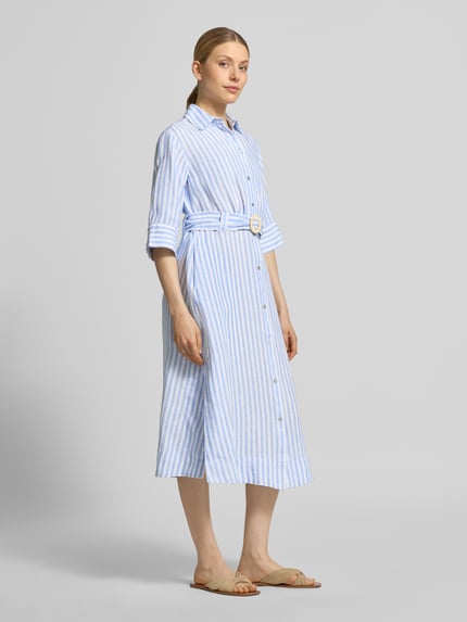 Modelka nosi Hemdblusenkleid aus Leinen mit Gürtel od Christian Berg Woman, niebieskie i białe paski, pasek, krój slim fit, długość midi, lekka faktura, szerokość w rozmiarze 36: 45 cm, długość pleców: 118 cm, długość rękawa: 35 cm, widok całej sylwetki z przodu.