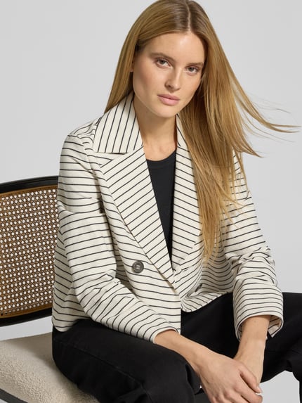 Frauenmodel trägt Blazer mit Reverskragen und Leistentaschen von Luisa Cerano, cremeweiß mit schwarzen Streifen, Nahaufnahme Oberkörper. Gerader Schnitt, Doppelreiher, Rückenlänge 58 cm, Brustweite 53 cm, Ärmellänge 61 cm.