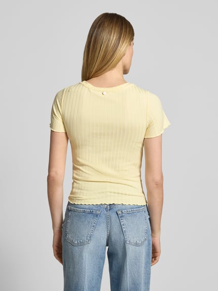 Frauenmodel trägt T-Shirt aus Viskose-Mix mit Rundhalsausschnitt von Rich & Royal, Strukturmuster, Straight Fit, Stretch-Anteil, Rückenlänge 51 cm bei Größe S, sanftes Gelb, feine Rippenstruktur, Ganzkörperansicht Rückansicht.
