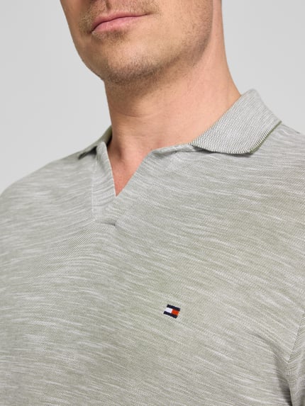 Männermodel trägt Regular Fit Poloshirt aus reiner Baumwolle von Tommy Hilfiger in Melange-Optik mit Logo-Stitching, Nahaufnahme Oberkörper.