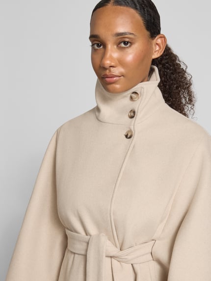 Frauenmodel trägt Loose Fit Poncho mit Bindegurt Modell 'AIKEN' von PIECES in Beige, Webware, Stehkragen, unifarben, Nahaufnahme Oberkörper.