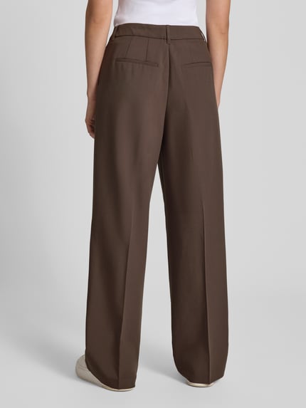 Männermodel trägt Wide Fit Hose mit Viskose-Anteil Modell 'Aya Ellis' von JJXX, braun, glatte Struktur, Ganzkörperansicht Rückansicht, Szerokość w rozmiarze S/32: 37 cm, długość nogawki wewnętrznej: 77 cm, elastyczny materiał, zakładki i kanty, zapięcie na hak i zamek