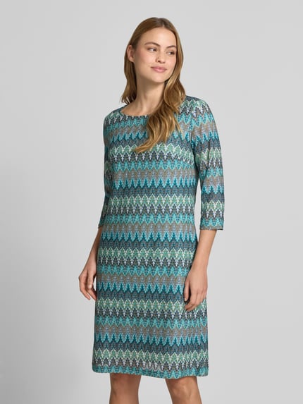 Modelka kobieca ma na sobie Regular Fit Kleid in Strick-Optik od Betty Barclay, wzór zygzakowaty w niebieskich i zielonych odcieniach, długość do kolan, dekolt w łódkę, rękaw 3/4, długość pleców w rozmiarze 36: 98 cm, szerokość w rozmiarze 36: 46 cm, długość rękawa w rozmiarze 36: 45 cm, widok całej sylwetki z przodu