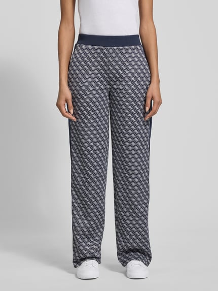 Frauenmodel trägt Wide Leg Sweatpants im Allover-Look Modell 'MAYA' von Guess Activewear mit elastischem Bund, Ganzkörperansicht von vorne.
