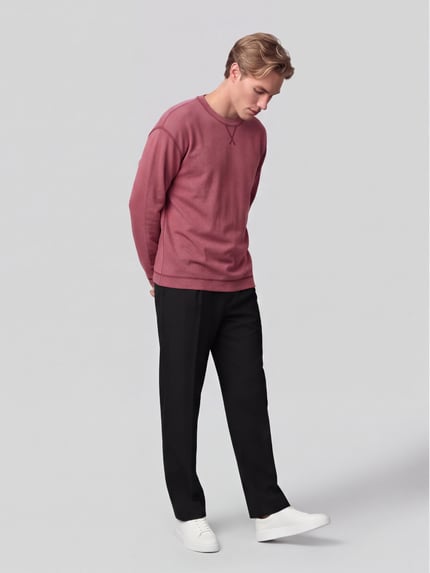 Männermodel trägt Langarmshirt mit Waffelstruktur von ARMEDANGELS in Unifarbe, Regular Fit, Rundhals, schwarze Hose, Ganzkörperansicht von vorne.