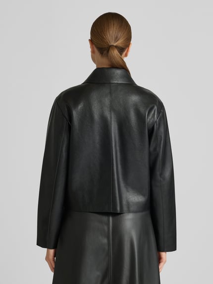 Frauenmodel trägt Jacke in Leder-Optik Modell 'SABINA' von Mango, schwarz, Regular-Fit, Hemdblusenkragen, Knopfleiste, Pattentaschen, Rückenlänge 52 cm, Schulterbreite 41 cm, Brustweite 48 cm, Ärmellänge 58 cm, Ganzkörperansicht Rückansicht.