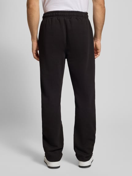 Männermodel trägt schwarze Sweatpants mit elastischem Bund von Pegador aus Baumwoll-Mix, Label-Stitching, Ganzkörperansicht Rückansicht.