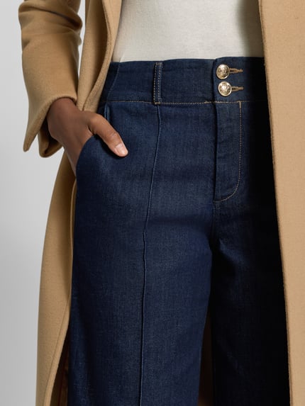 Frauenmodel trägt Regular Fit Marlenehose aus Baumwoll-Mix von s.Oliver BLACK LABEL in Dunkelblau mit heller Naht, Nahaufnahme Oberkörper.