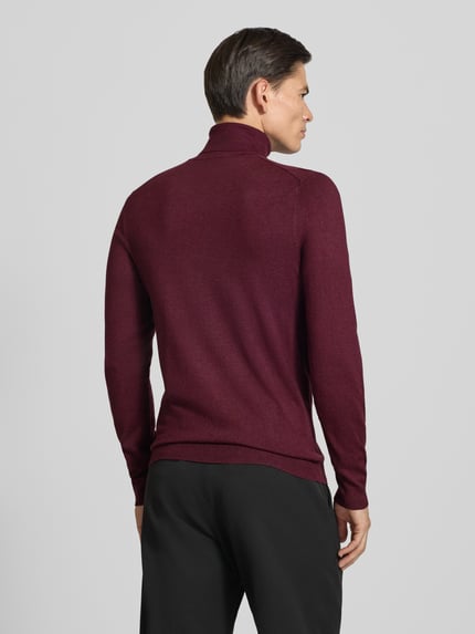 Männermodel trägt Slim Fit Rollkragenpullover aus Viskose-Mix mit Rippbündchen von MCNEAL, weinrot, glatte Textur, Ganzkörperansicht Rückansicht.