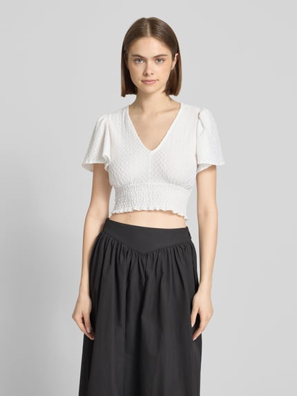 Frauenmodel trägt Regular Fit Crop Top mit Strukturmuster Modell 'HANNAH' von Only, Optik: Unifarben, V-Ausschnitt, Schmetterlingsärmel, gesmoktes Brustband, Strukturmuster, schwarz-weiß, Ganzkörperansicht von vorne.