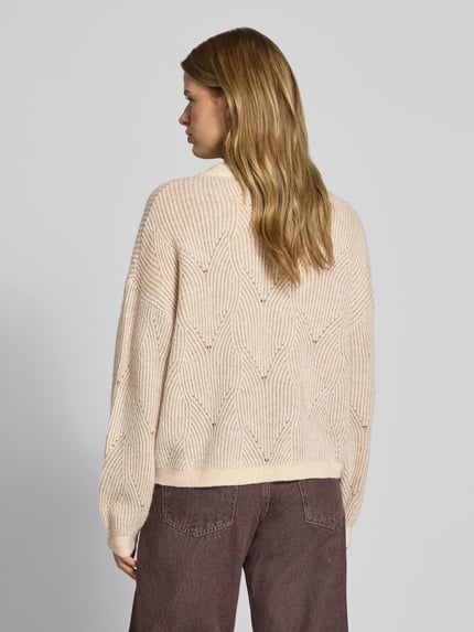 Frauenmodel trägt Pullover mit plastischer Strickstruktur von PIECES, beige, geometrisches Allover-Muster, gerippte Abschlüsse, Ganzkörperansicht Rückansicht.