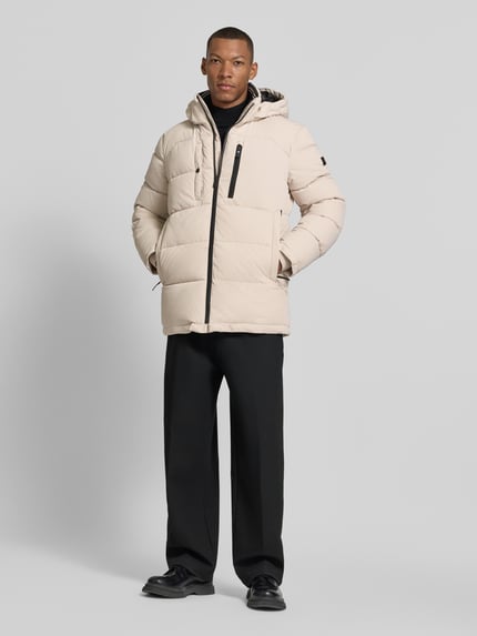 Männermodel trägt Regular Fit Steppjacke mit Brusttasche von s.Oliver RED LABEL in Beige mit Struktur, unifarben, Longline, Ganzkörperansicht von vorne.