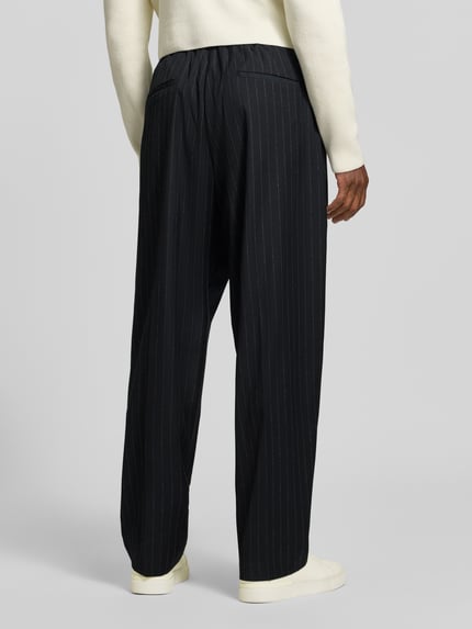 Männermodel trägt Stoffhose mit Bügelfalte Modell 'LEON' von Antony Morato, Wide Fit, Material-Mix, Ganzkörperansicht Rückansicht.