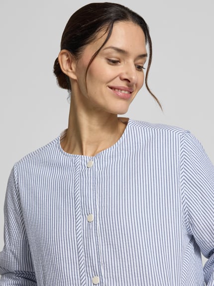 Frauenmodel trägt Jacke mit Rundhalsausschnitt Modell 'GABI' von ECOALF aus reiner Baumwolle, feine weiße und blaue Streifen, Nahaufnahme Oberkörper.