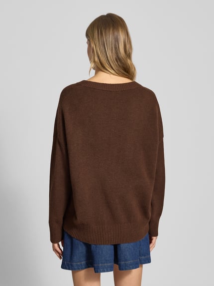 Frauenmodel trägt Regular Fit Strickpullover mit Woll-Anteil Modell 'MARI' von Only, Melange-Optik, V-Ausschnitt, Langarm, gerippt, Strick, Ganzkörperansicht Rückansicht.