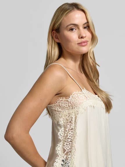 Frauenmodel trägt Relaxed Fit Top mit Spitzenbesatz Modell 'CHARM LACE SINGLET' von VERO MODA, unifarbene Optik, Spitze am V-Ausschnitt, Seitenschlitze, Nahaufnahme Oberkörper.