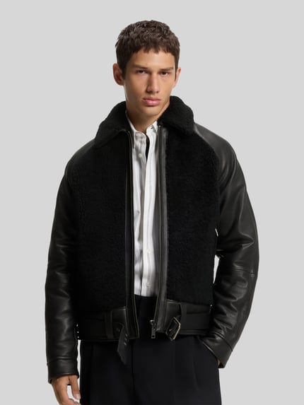 Männermodel trägt schwarze Lederjacke Modell 'Laran' mit Schnalle von HUGO, Struktur, Glattleder und Fleece, Ganzkörperansicht von vorne