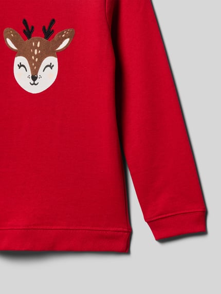 Mädchen trägt Sweatshirt mit Motiv-Print von Blue Seven in Rot, Reine Baumwolle, Lockerer-Schnitt, Gerippte-Abschlüsse, Rundhalsausschnitt, Nahaufnahme Oberkörper.