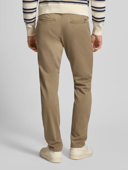 Mężczyzna nosi Stoffhose mit Gesäßtaschen Modell 'MARCO' od Jack & Jones, beżowa, bawełna z elastanem, widok całej sylwetki od tyłu.