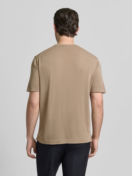 Männermodel trägt T-Shirt mit geripptem Rundhalsausschnitt von CRUNA in beige, regular fit, katoen, ruglengte 70 cm, Ganzkörperansicht Rückansicht.