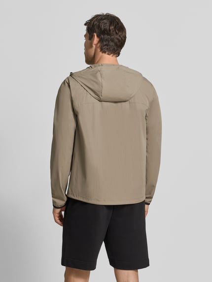 Männermodel trägt Regular Fit Trainingsjacke mit Label-Print Modell 'OW_Airynix JT HD 2' von BOSS Green in Beige, glatte Struktur, Ganzkörperansicht Rückansicht.